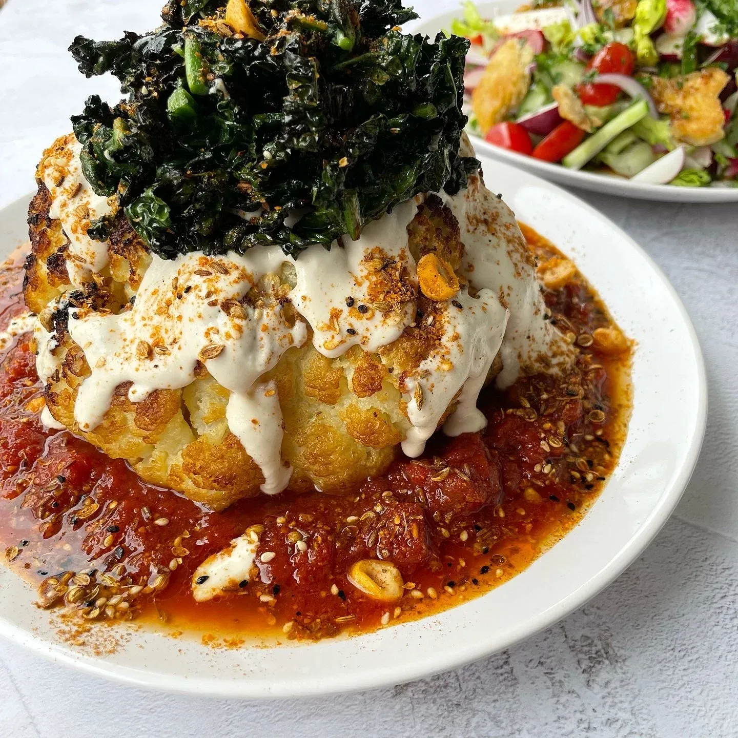 Whole roast cauliflower, spiced tomato sauce, tahini yoghurt, dukkah and crispy kale